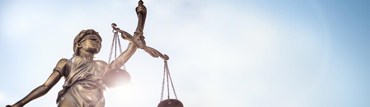 statue of Lady Justice with scales of justice and sky background