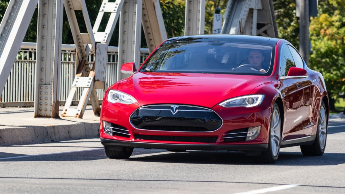 Red Tesla crosses a bridge.