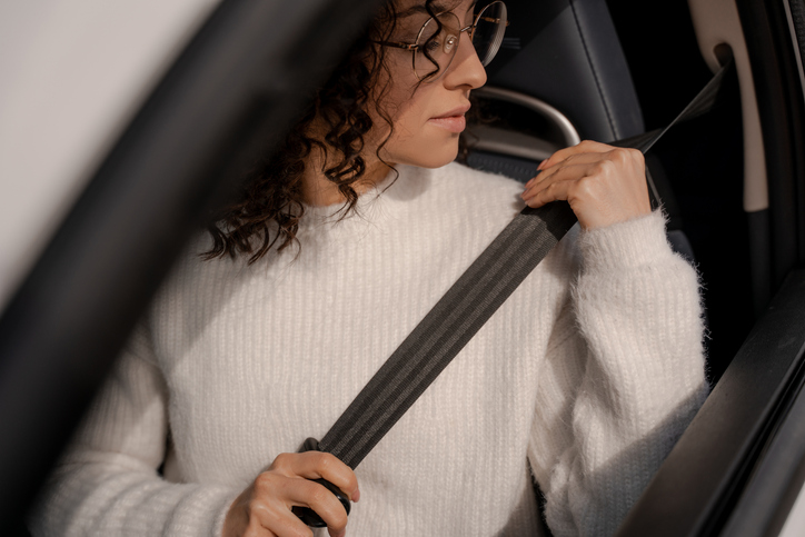 woman adjusting her seat belt - types of seatbelt defects and how they cause injuries
