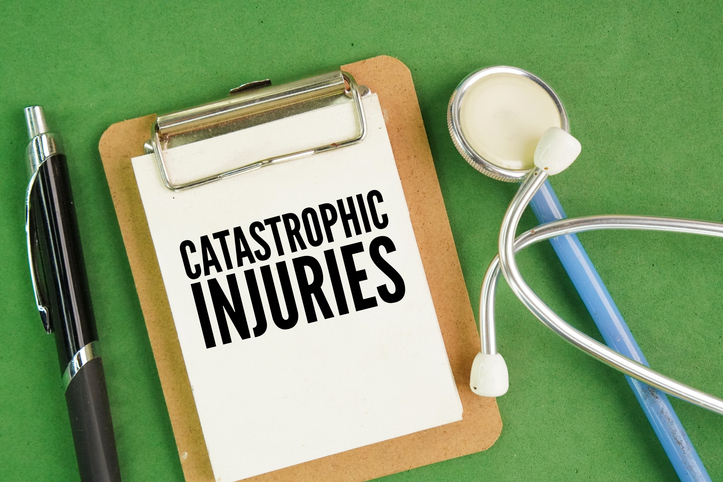 Stethoscope, pen and paper board with word catastrophic injuries